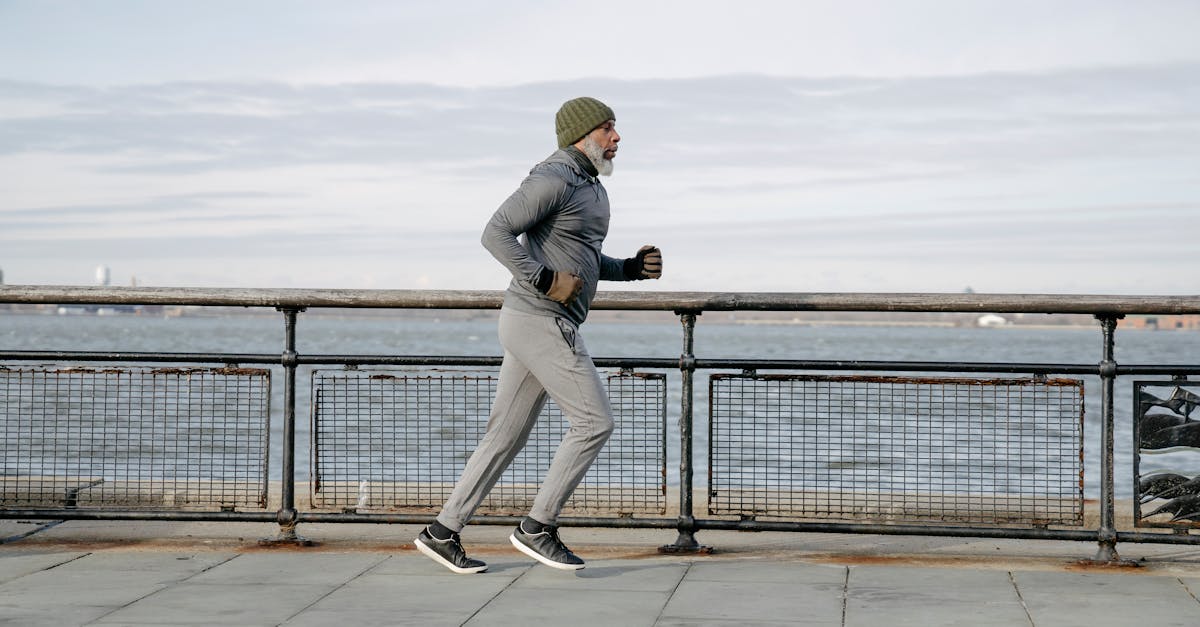 Elderly man running along waterfront, embracing a healthy lifestyle and exercise routine.